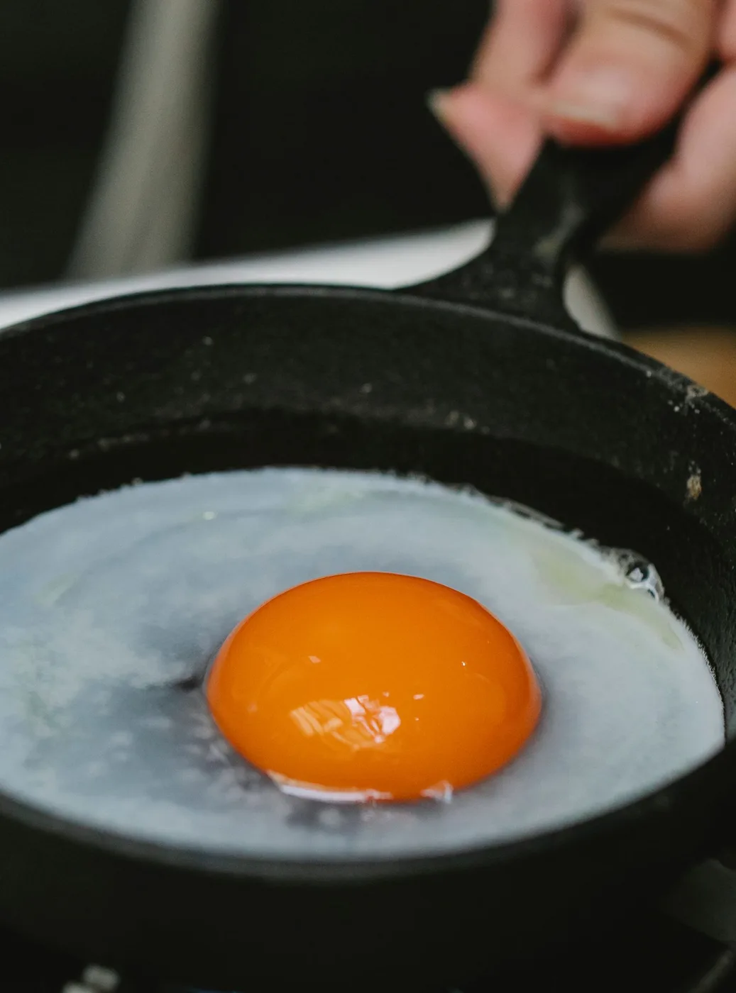 An egg cooking in a dark skillet during breakfast preparation